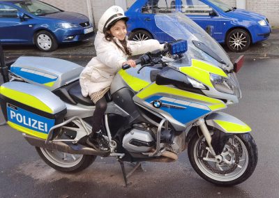 Little girl sitting with police cap on police motorcycle