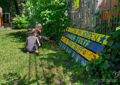 Zwei Kinder auf einer Wiese - ein Schild mit der Aufschrift Stern im Norden Kindertreff Teentreff - Kindern in Deutschland helfen