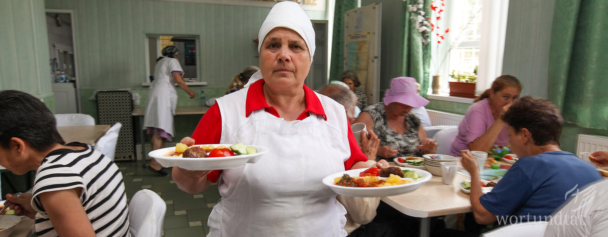 Eine Helferin serviert Mittagessen im sozial-diakonischen Zentrum Gloria in Ceadîr-Lunga, Republik Moldau. Mann zeigt Roma-Jungen, wie er mit Plättchen richtig zählen lernt.