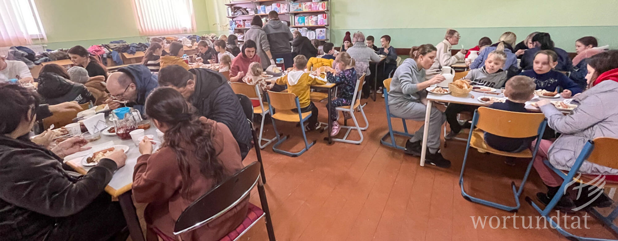 Hilfe für ukrainische Flüchtlinge in der Republik Moldau und Rumänien leisten die wortundtat-Partner. Viele Menschen an Tischen in einem Speisesaal
