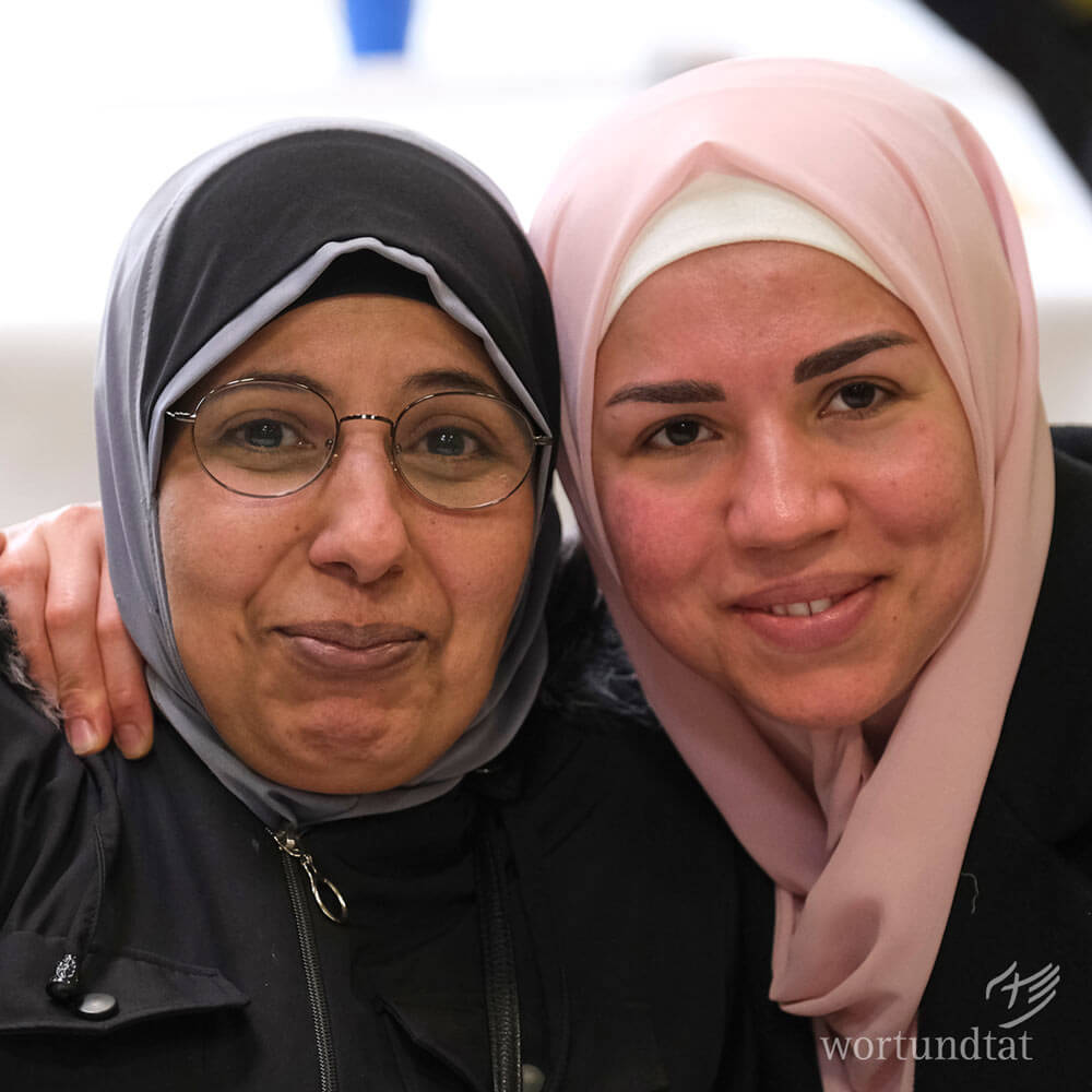 Zwei Frauen mit Kopftuch lächeln in die Kamera