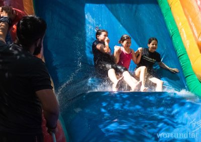 drei Mädchen rutschen auf einer aufblasbaren Wasserrutsche
