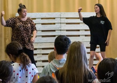 two young women dancing in front of group of young people in front of