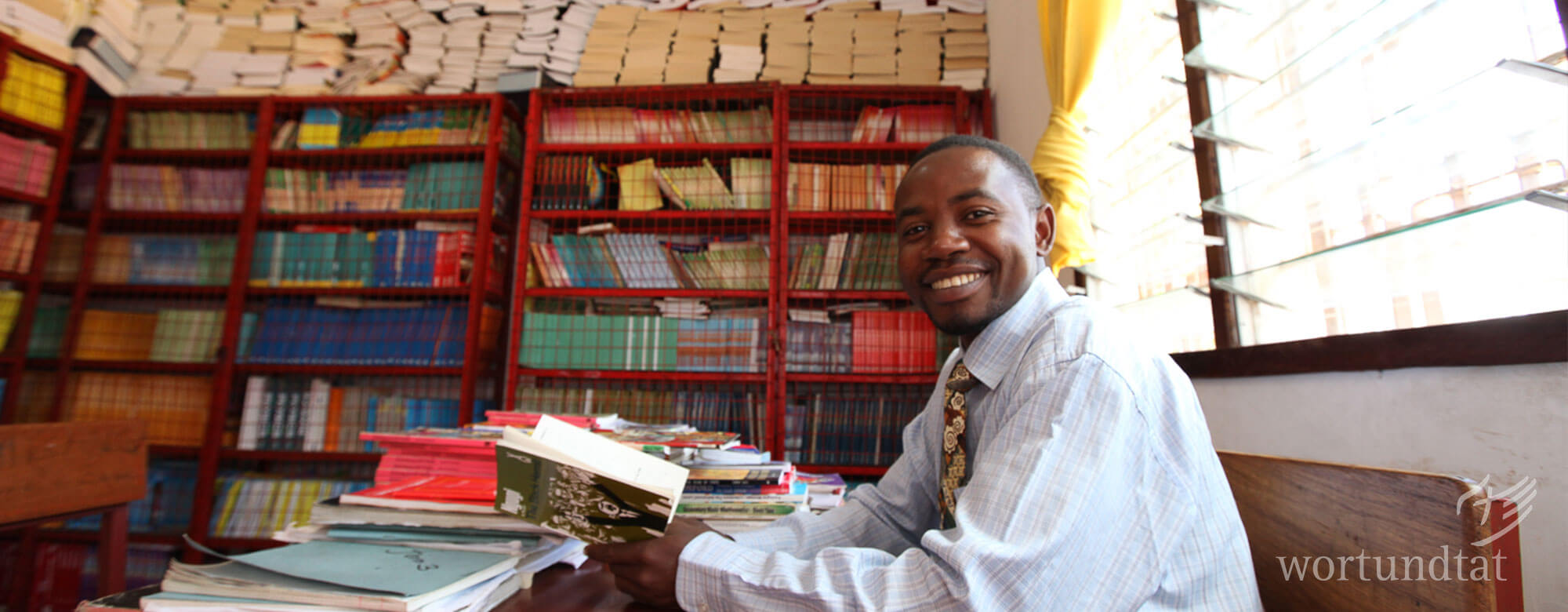 Mann in einem Raum mit Regalen voller Schulbücher