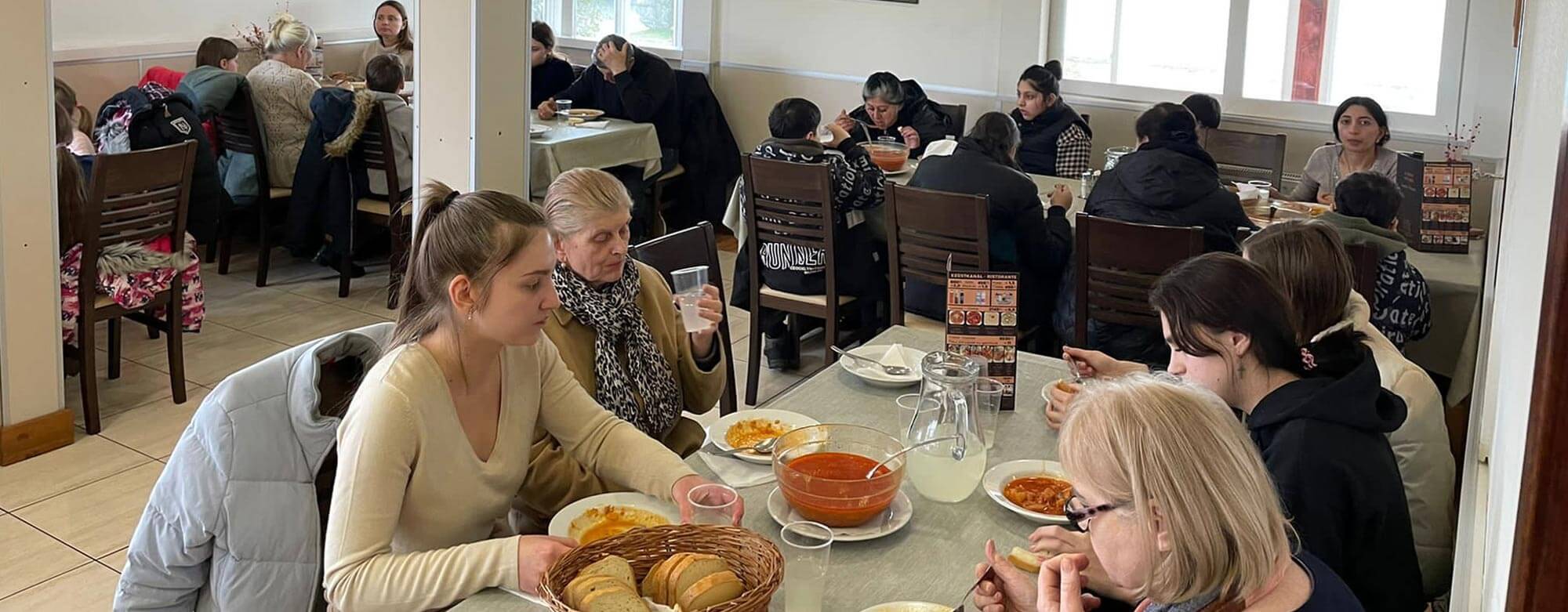 Frauen und in Kinder in einem Speisesaal beim Essen