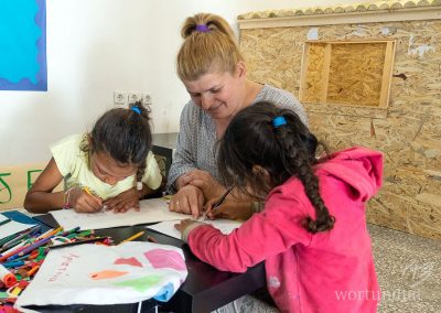 Caregiver and two little girls sit at table and paint