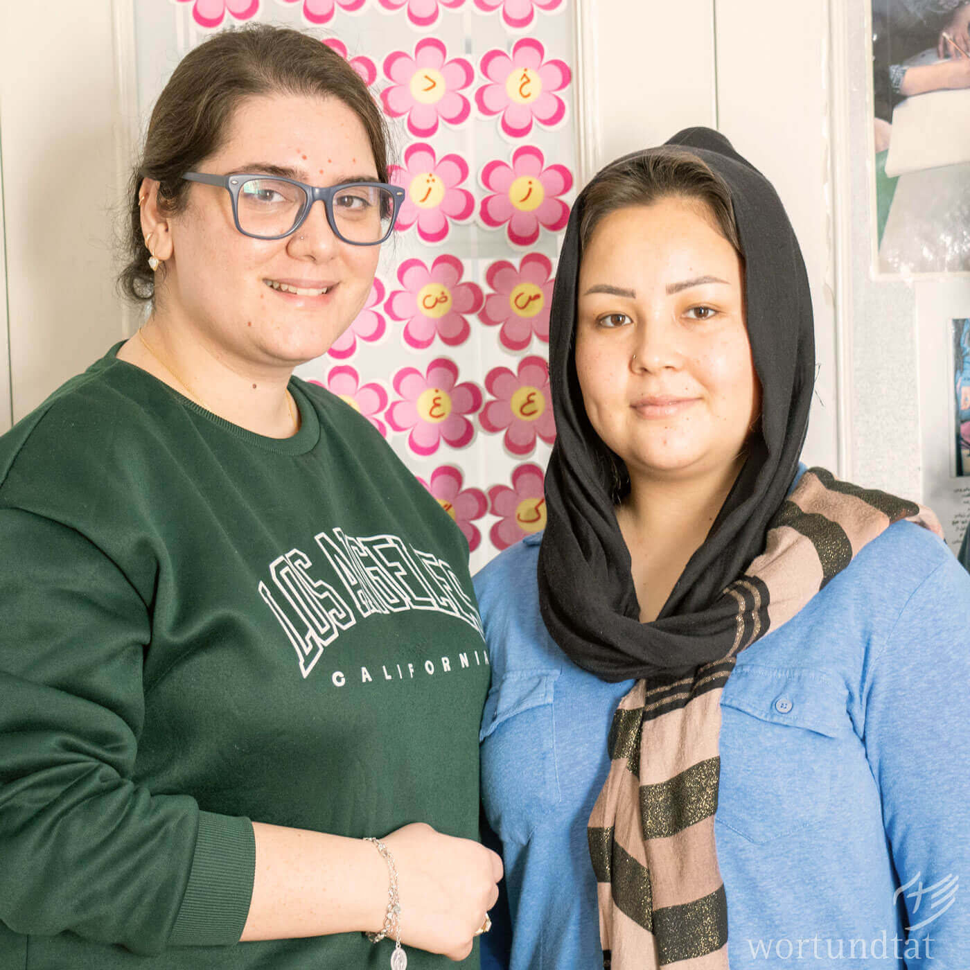 Ghazal (left) helps Saade learn to read and write and also accompanies her in many other matters. Two women look into camera