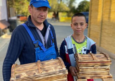 Man and boy hold two finished homemade wooden boxes in hands