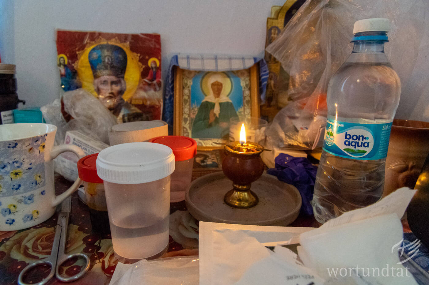 Kerze, Heiligenbilder, medizinische Utensilien, Flasche Wasser