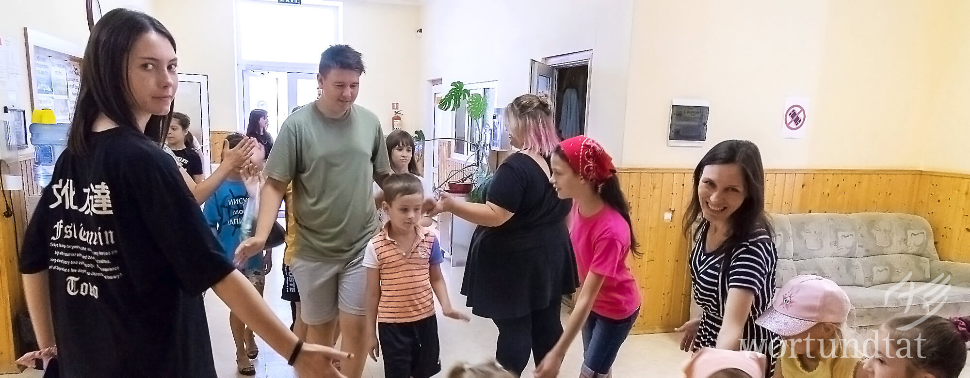 Young woman high-fives children as they arrive at a daycare center